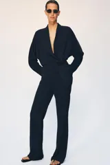 Blazer de corte fluido confeccionada en mezcla de viscosa, con cuello solapa, manga larga con puños abotonados y cierre frontal cruzado con botón único.