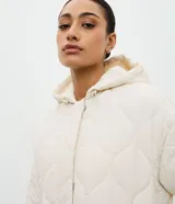 Campera acolchada de microfibra color crema, con diseño capitoneado, capucha integrada, cierre frontal oculto y cinturón ajustable del mismo tejido para entallar la silueta.