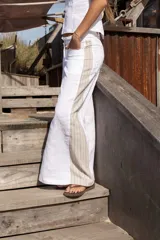 Pantalón blanco de lino con corte de piernas anchas, cadera al cuerpo y cintura media. Aplique de lino rayado en los costados en forma triangular.