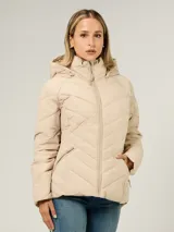 Campera ligera acolchada de Tommy Hilfiger en color beige. Presenta un diseño con costuras en forma de V, cuello alto con capucha ajustable mediante cordones, cierre frontal de cremallera y dos bolsillos laterales con cierre. Cuenta con el logo de la marca bordado en el pecho.