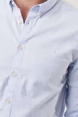 Camisa de hombre color crema, de corte clásico, con cuello abotonado y mangas largas.