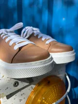 Championes acordonados de cuero color caramelo con suela blanca.