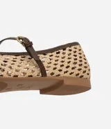 Zapatilla tipo bailarina con capellada tejida con efecto rafia color beige, punta redonda, tira fina marrón con hebilla y suela marrón.