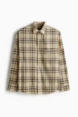 Camisa de corte relajado, color beige con patrón de cuadros en tonos negros y grises, manga larga, cuello inglés, cierre frontal de botones y bolsillo en el pecho.