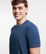 Remera deportiva de hombre con tecnología dry fit, cuello redondo y manga corta. Presenta un diseño liso en color beige con una pequeña etiqueta decorativa en el dobladillo.