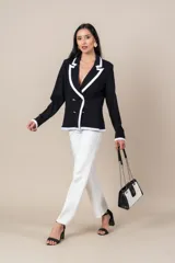 Blazer negro cruzado con vivos blancos, botones dorados, bolsillos delanteros y detalle de cuatro botones dorados en las mangas.