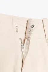 Jeans de tiro alto, pierna ancha y largo al tobillo, en denim celeste claro con efecto lavado. Presenta costura marcada en el centro de cada pierna y cierre frontal con cremallera y botón.