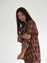 Conjunto de pijama a cuadros con ribetes en color lila, compuesto por camisa de manga larga con botones y pantalón largo.