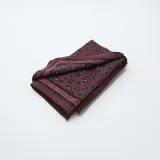 Pañuelo de forma triangular con estampado de leopardo en tonos bordó y negro, con un borde decorativo geométrico.