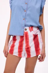 Short de tiro alto con estampado de rayas verticales rojas sobre fondo blanco, con efecto pincelada. Presenta detalles de texto manuscrito en los bordes y cierre frontal con botón.