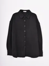 Sobrecamisa de gamuza color negro, de corte oversize, con cuello camisero y cierre frontal de botones.