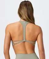 Top deportivo Fabletics modelo PureLuxe color verde militar, con diseño cruzado en la parte delantera y tirantes halter.