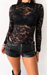 Body de encaje negro con cuello alto y mangas largas, diseñado con un ajuste al cuerpo.