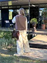 Chaleco tejido de punto en color chocolate, con cuello redondo y diseño sin mangas. Presenta un aplique frontal decorativo compuesto por tres figuras en forma de rombo en tonos tierra, bordeadas con hilo crudo.