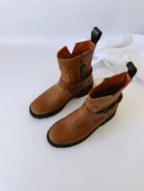 Bota de cuero color marrón con suela de goma negra, cierre lateral y pulsera desmontable con hebilla.