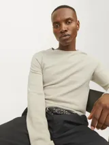 Sweater de manga larga con cuello redondo, confeccionado en tejido de punto con textura estructurada. Presenta un diseño minimalista con un pequeño parche de marca en el ruedo inferior.