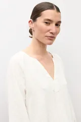 Blusa negra de manga larga con diseño de tejido plumeti y escote en V.