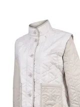 Campera reversible acolchada de color beige, con capucha desmontable, mangas largas y bolsillos frontales aplicados. Cuenta con cierre de botones y diseño matelasse.