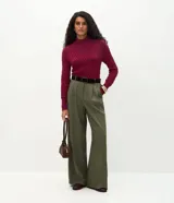 Suéter de punto color crema con textura en zigzag, cuello alto y mangas largas con puños ajustados.