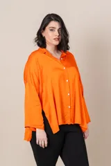 Camisa italiana de satén color naranja, de calce holgado, con manga caída y presilla para sujetar la manga. Presenta tajos a los costados y botones de nácar.
