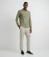 Camisa de manga larga confeccionada en sarga de algodón, con cuello clásico, cierre frontal abotonado y dos bolsillos frontales con solapa y botón.