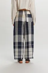 Pantalón Tokyo de lino con diseño a cuadros en tonos azul marino, beige y blanco. Presenta un corte amplio y relajado, cintura con cierre frontal de botón y tiras decorativas colgantes.