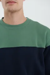 Sweater deportivo de hombre con escote redondo, diseño colorblock con la parte superior en gris claro y el cuerpo y mangas en negro. Presenta puños y cintura elastizados.