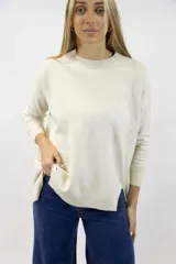 Buzo de punto color beige melange, de cuello redondo, mangas largas y corte holgado con aberturas laterales en el dobladillo.