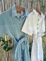 Vestido camisero corto de jean celeste con botones dorados y lazo en la cintura.