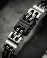 Pulsera de eslabones rectangulares combinados en acero plateado y acero negro, con diseño moderno y cierre integrado.