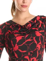 Vestido corto de seda fría con estampado floral en tonos rojo y negro. Presenta cuello volcado, mangas tres cuartos y un detalle de drapeado lateral en la cintura.