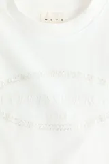 Remera deportiva de punto de algodón color blanco, de corte oversized con mangas cortas, hombros caídos y cuello redondo ribeteado. Presenta un estampado frontal en relieve dentro de un óvalo.