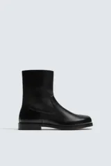 Bota de caña media fabricada en piel, con diseño de horma cuadrada, cierre mediante cremallera lateral y suela con ligero tacón.