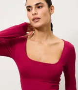 Blusa cropped deportiva femenina Get Over, confeccionada en microfibra de poliamida y elastano, de color fucsia, con escote cuadrado, manga larga y puños con abertura para pulgar.