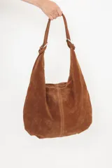 Bolso hobo de cuero gamuzado color marrón, con correa de hombro y cierre superior.