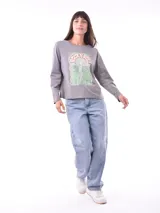 Remera de manga larga color azul, con cuello redondo y un estampado central de flores en tonos pastel sobre un recuadro gris claro.