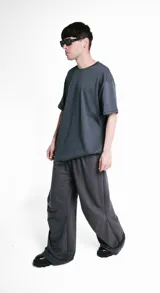 Pantalón unisex gris con pretina elástica, bolsillos laterales y pinzas horizontales en las rodillas.