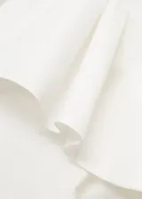 Vestido midi de algodón con diseño asimétrico de un solo hombro, decorado con un volante. Presenta aberturas laterales tipo cut-out en la cintura y una falda evasé con bolsillos laterales.