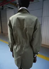 Parka verde militar de algodón, de diseño oversize con cuello camisero, manga larga, bolsillos con solapa en el pecho, bolsillos laterales y cordón ajustable en la cintura.