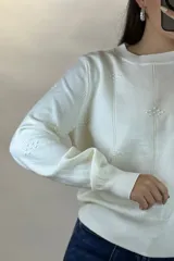 Buzo de hilo color verde menta, de cuello redondo y manga larga, con diseño de líneas verticales en relieve y pequeños detalles bordados.
