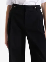 Pantalon de corte wide leg y largo completo, confeccionado en tejido de algodon con elastano. Presenta tablas en la cintura delantera, cierre metalico, ganchos pantaloneros y presillas con broches snap niquelados. Incluye bolsillos laterales y traseros.