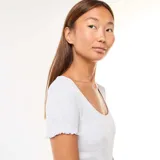 Camiseta gris de punto canalé, de manga corta y escote cuadrado con ribete ondulado.