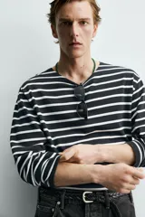 Camiseta de manga larga con ajuste relajado, confeccionada en tejido ligero de algodón. Presenta un diseño de rayas horizontales en color negro y blanco con cuello redondo.
