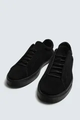 Zapatilla urbana de hombre con parte superior de piel con acabado en serraje color marrón. Presenta un diseño minimalista con cordonera oculta y suela de goma a contraste en color negro.
