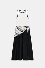 Vestido midi bicolor con parte superior blanca tipo musculosa con ribetes negros y falda negra evasé. Cuenta con un detalle de pañuelo a rayas en blanco y negro anudado en la cintura, bolsillos laterales y cierre con cremallera.