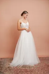Vestido largo blanco de alta costura, con corset estructurado de tirantes finos con apliques florales y falda amplia de tul con brillo.