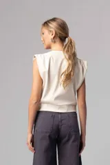 Top color beige de simil cuero liviano, con escote cruzado y acceso por cierre invisible lateral. Sin mangas con espalda cerrada y frunces en hombros.