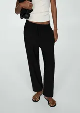 Pantalon de corte recto y tiro alto, confeccionado en tejido fluido. Presenta cintura elástica con cordón ajustable y bolsillos laterales.