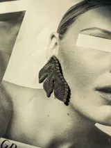 Aros con forma de media flor, color gris oscuro, con detalle de strass en el borde.