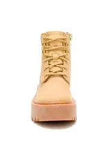 Bota de cuero color amarillo con diseño de plataforma alta y suela de goma dentada. Presenta cuello acolchado en color marrón oscuro, cierre con cordones y logo de la marca grabado en el lateral.